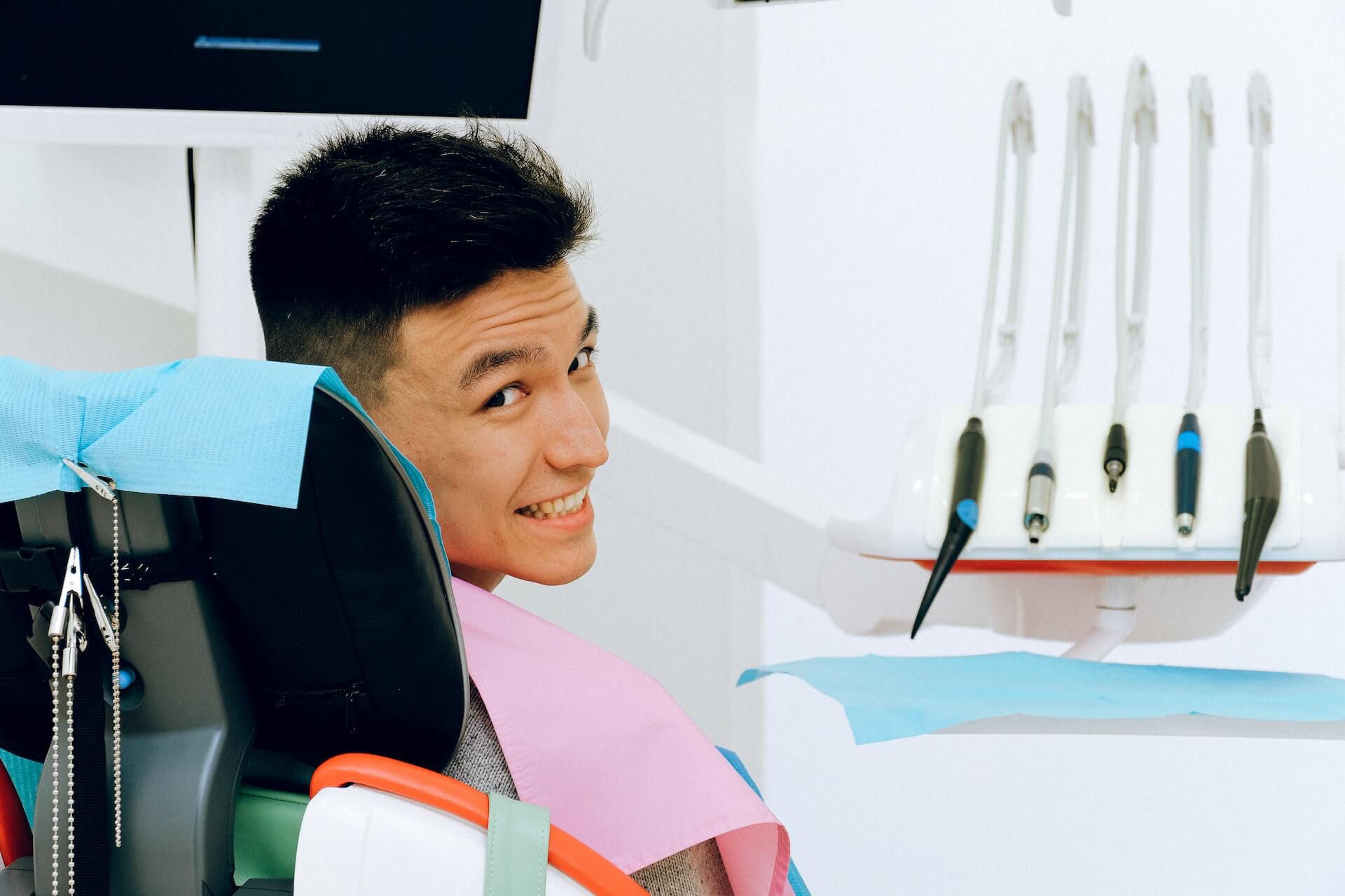 A new patient sits in a dentist’s chair and smiles.