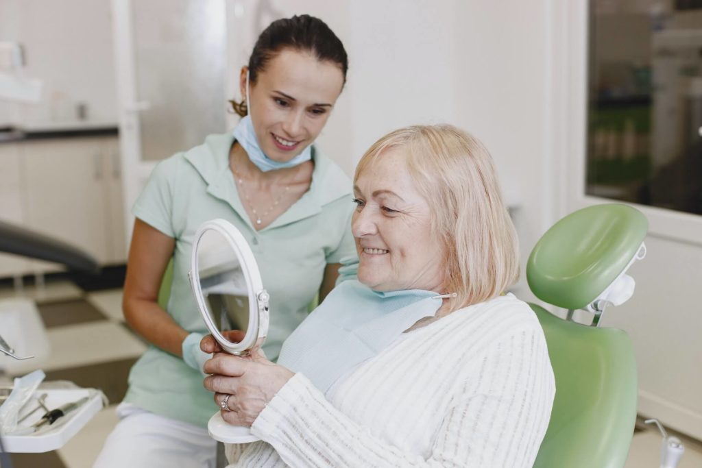 Dentist and patient looking at dentures in a mirror.