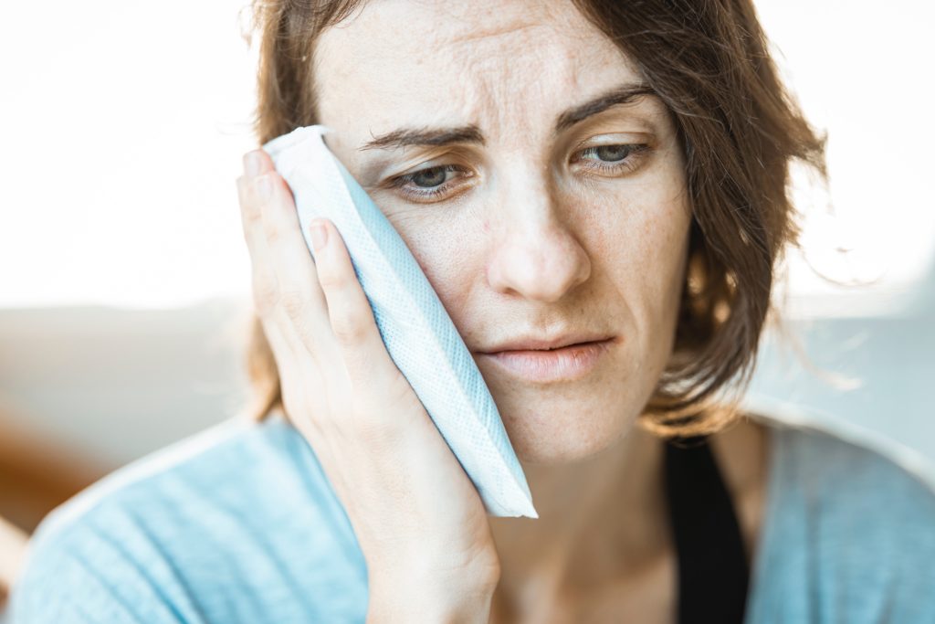 woman holding ice pack to cheek